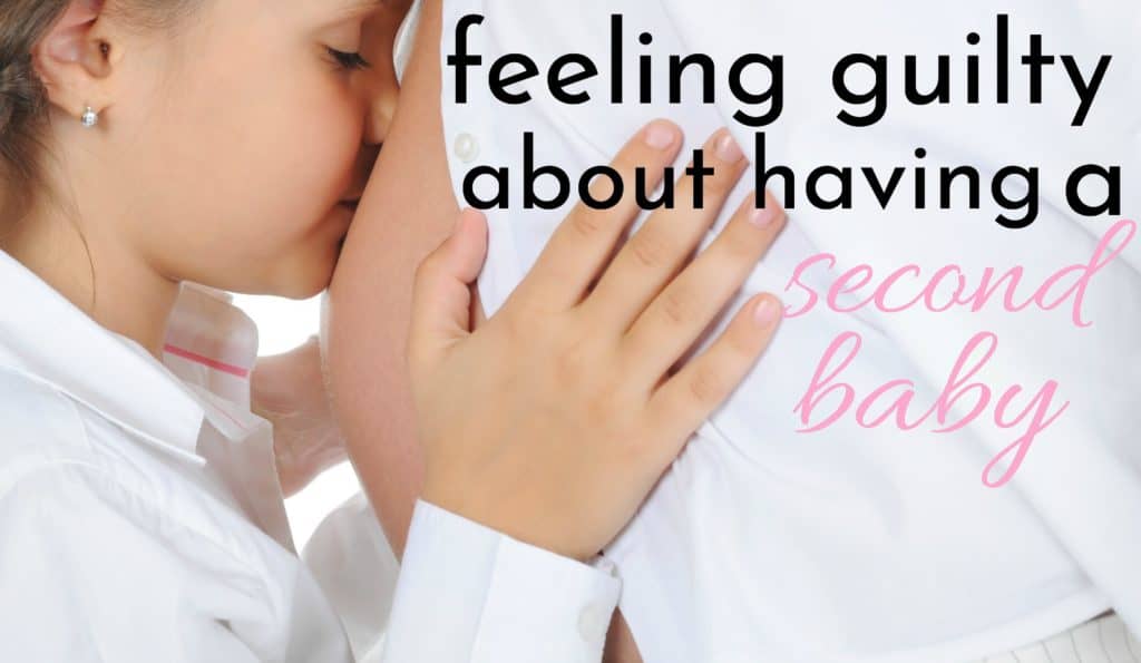 daughter in white touching pregnant belly of mom who feels guilty about having a second baby