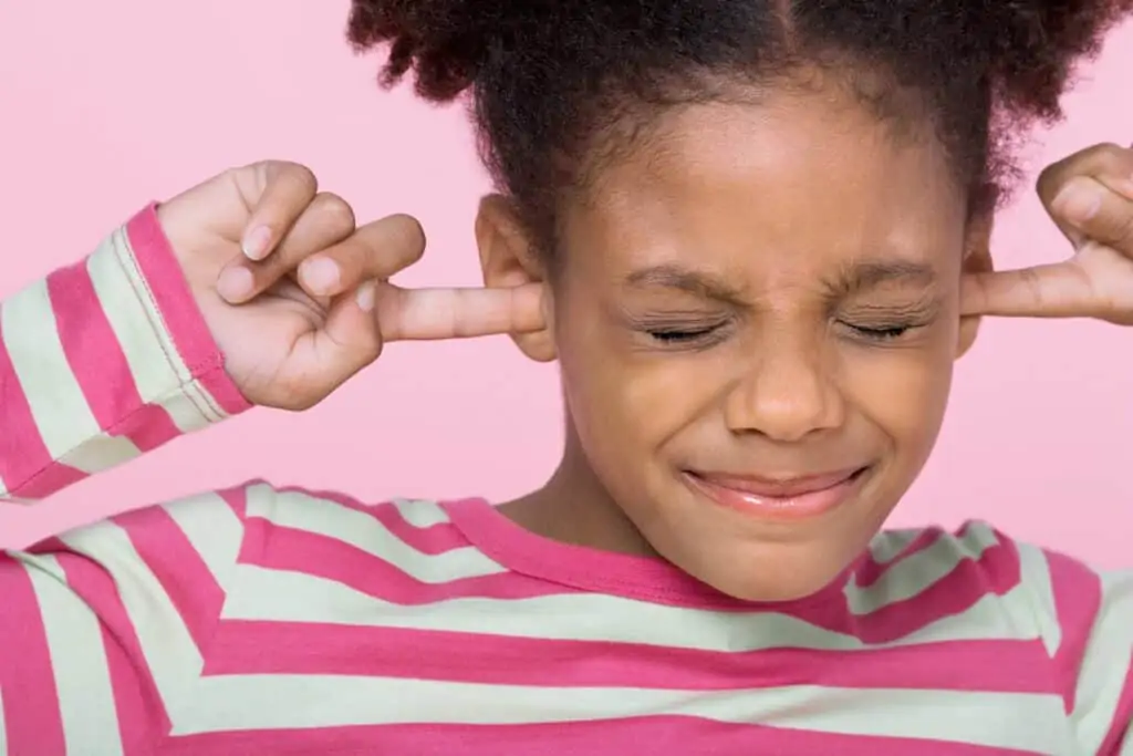 little girl upset with fingers in ears because of strict parents