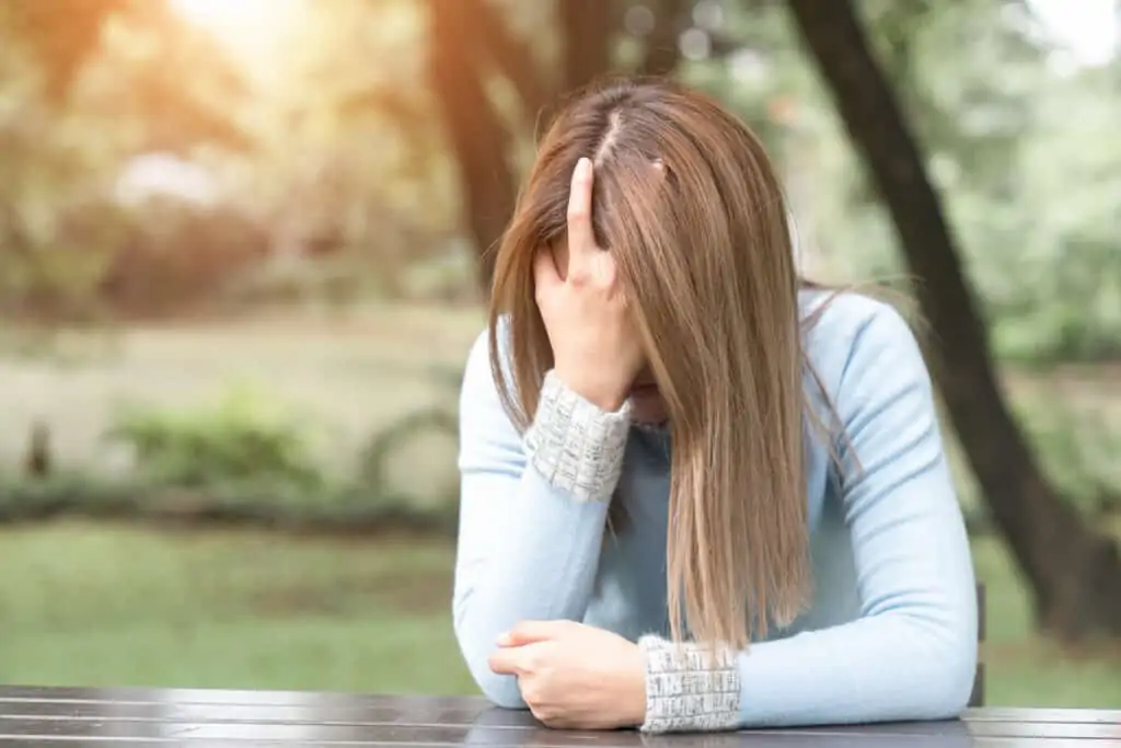 woman sitting at picnic table with her head in her hand sad why moms yell