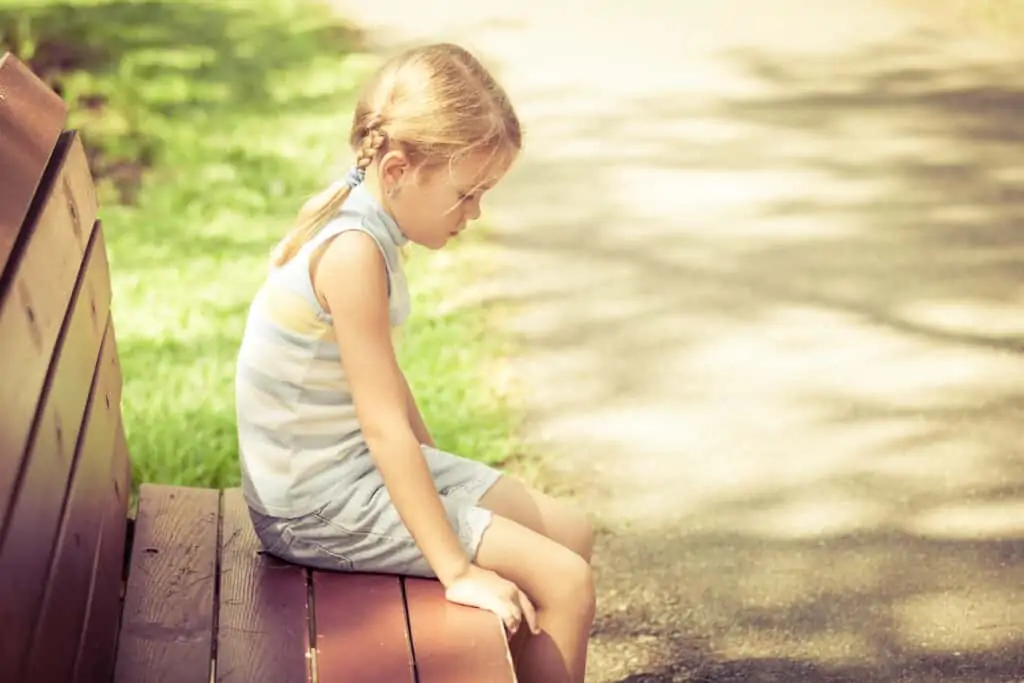 pretty little girl on bench sad because of strict parents