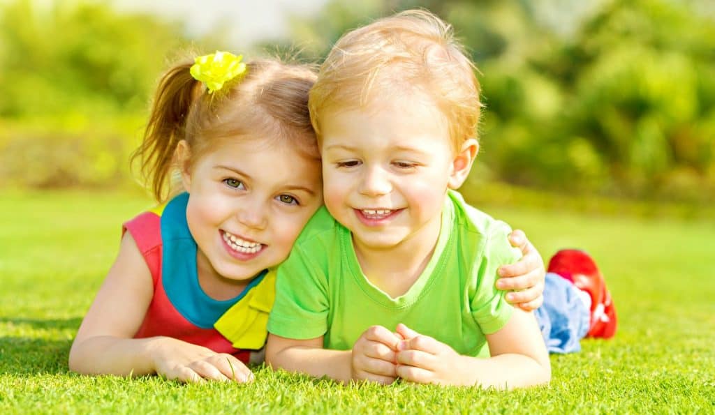 two children hugging on the green grass after resolving sibling conflict