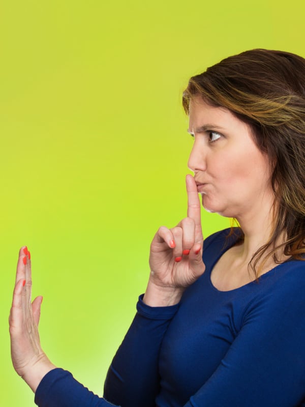 mom with finger to mouth saying quiet down to stop yelling at your kids